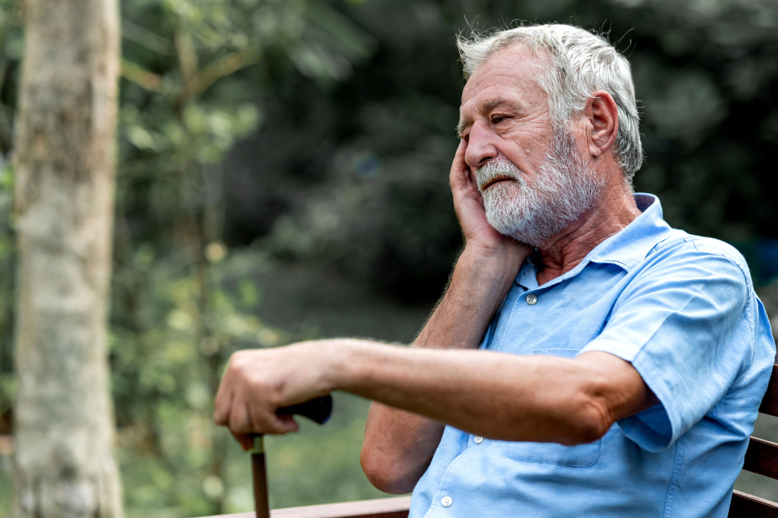 Lonely senior man sitting on park bench. Caucasian man. Thinking about the past.