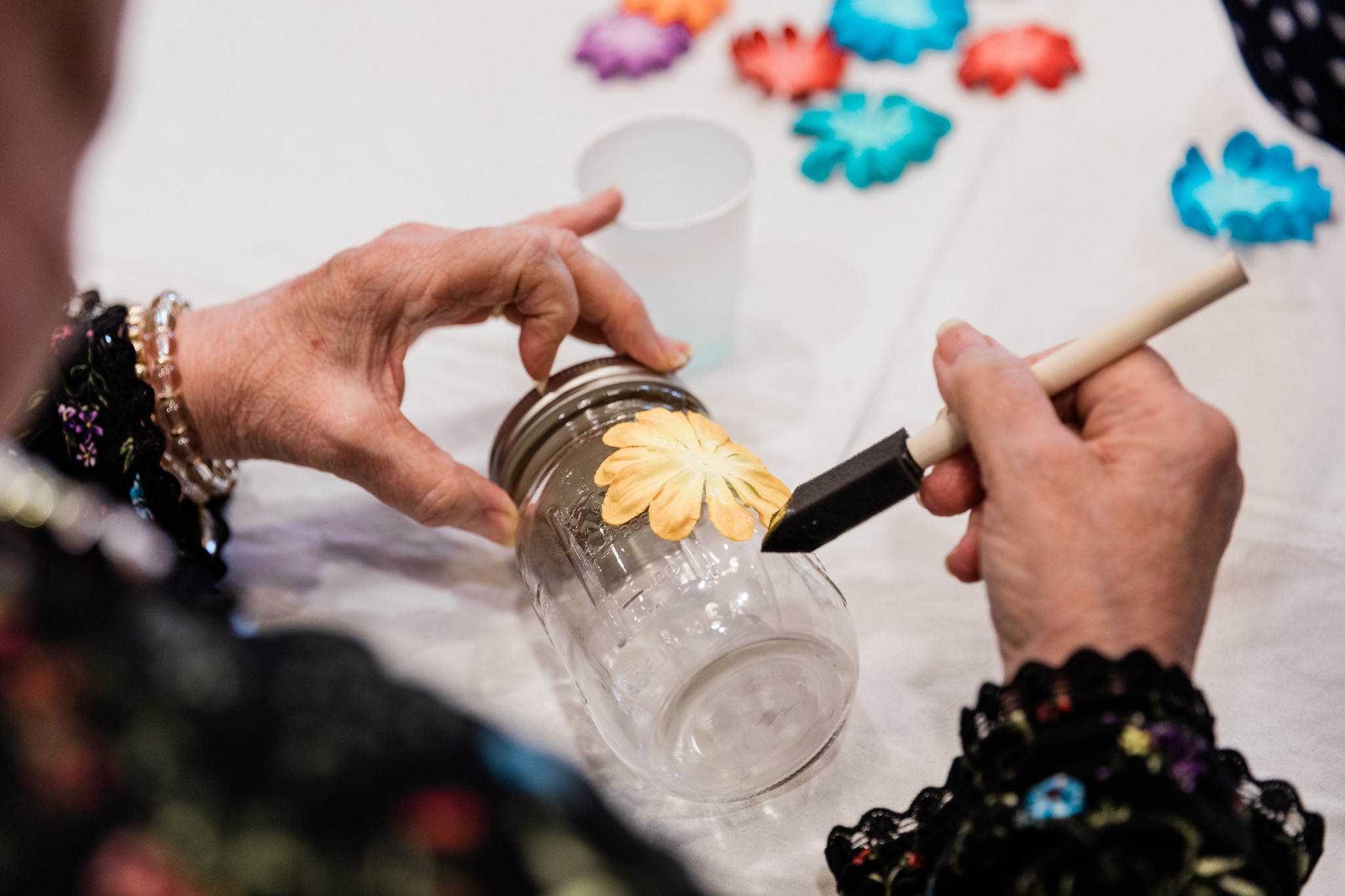A resident engaging in a fun activity at Grand Brook. Decorating a jar with flowers.