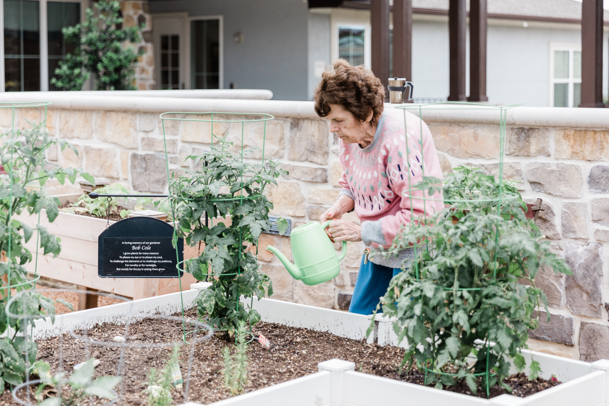 A senior woman at Grand Brook who is a resident watering the plants (gardening) for fun and it gives her comfort
