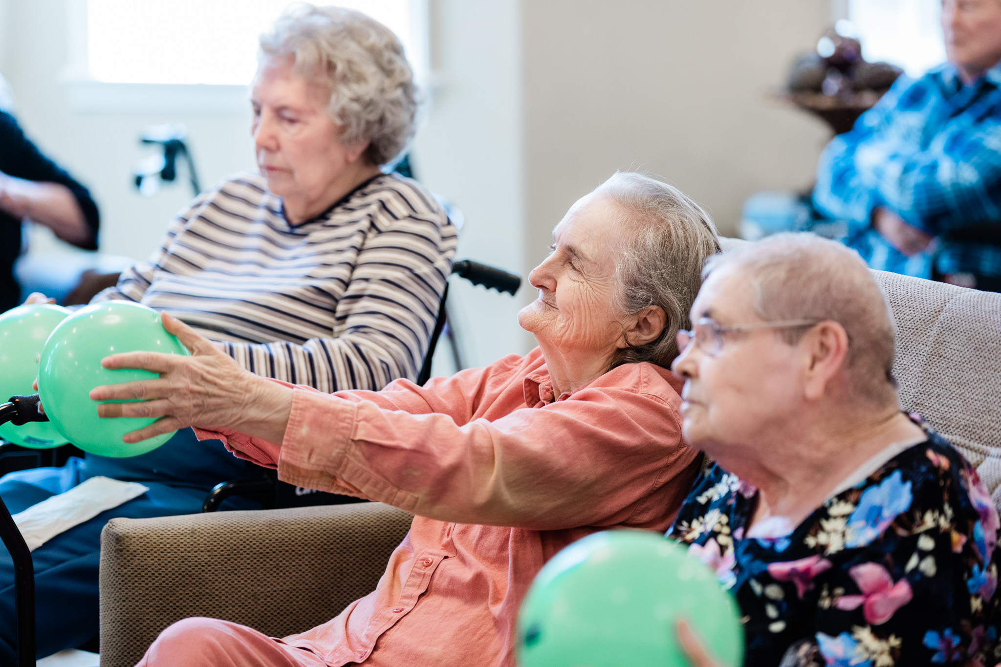 3 senior women at Grand Brook who are residents engaging in a fun balloon activity.