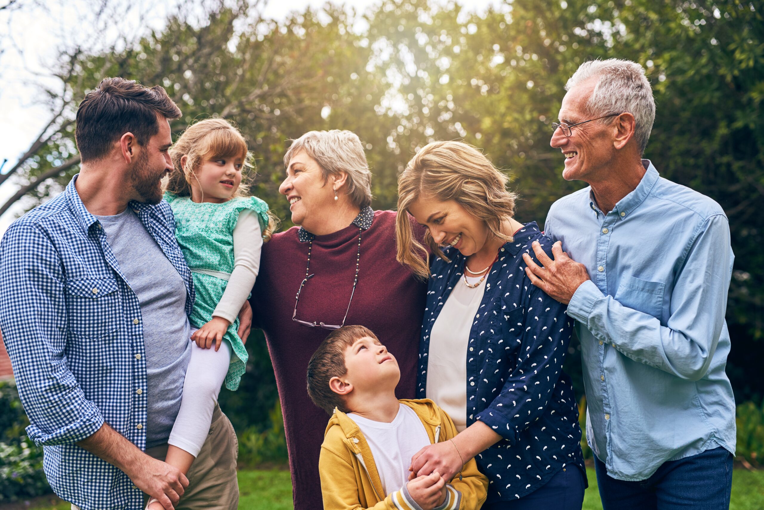 Shot of a multigenerational family outside. The grand parents have dementia and need memory care. the parents are going through anticipatory grief and considering memory care. 