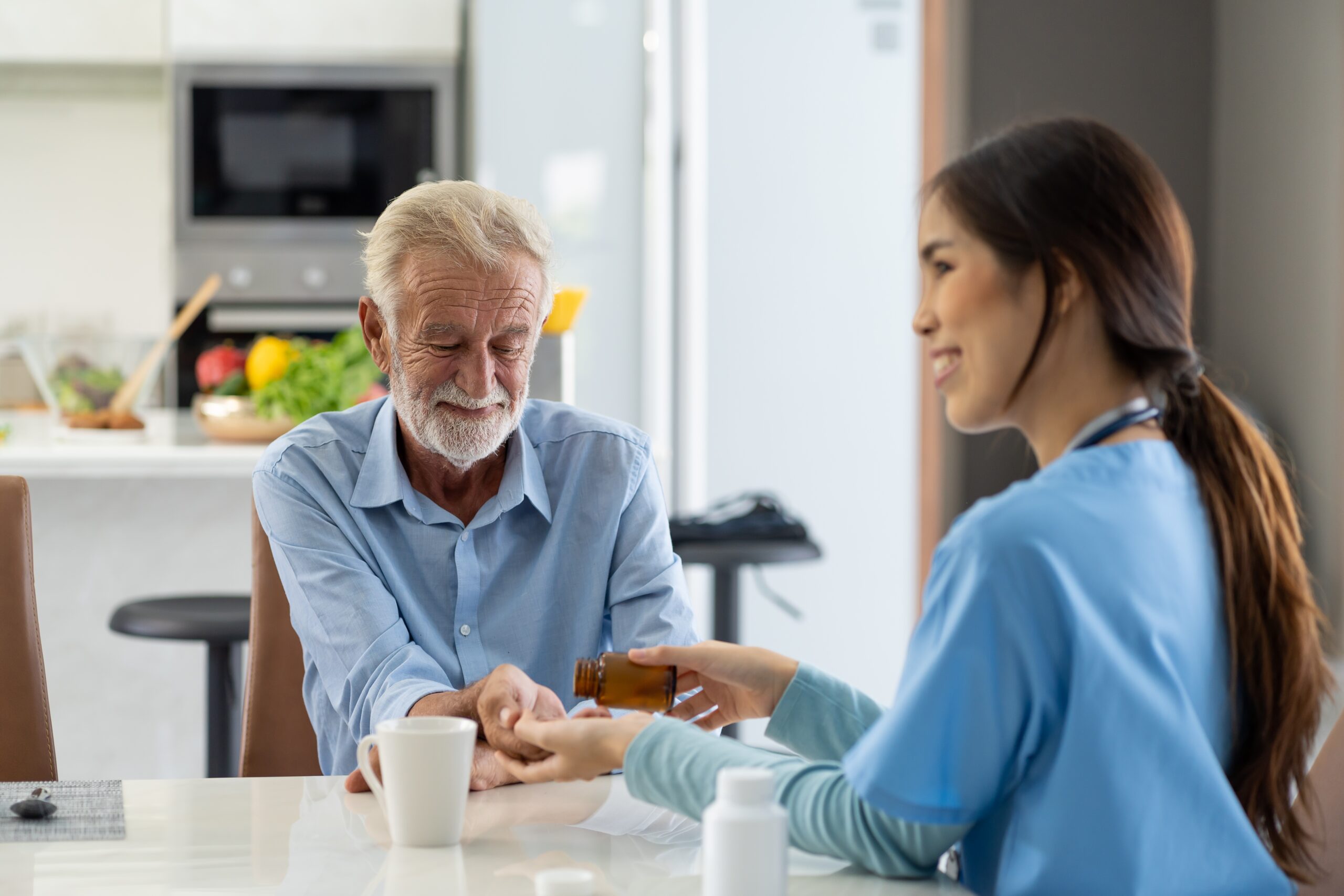 Caring Asian nurse giving medication and glass of water to senior old man patient at hospital. Friendly female doctor caring and giving medicine elderly man patient at nursing home.