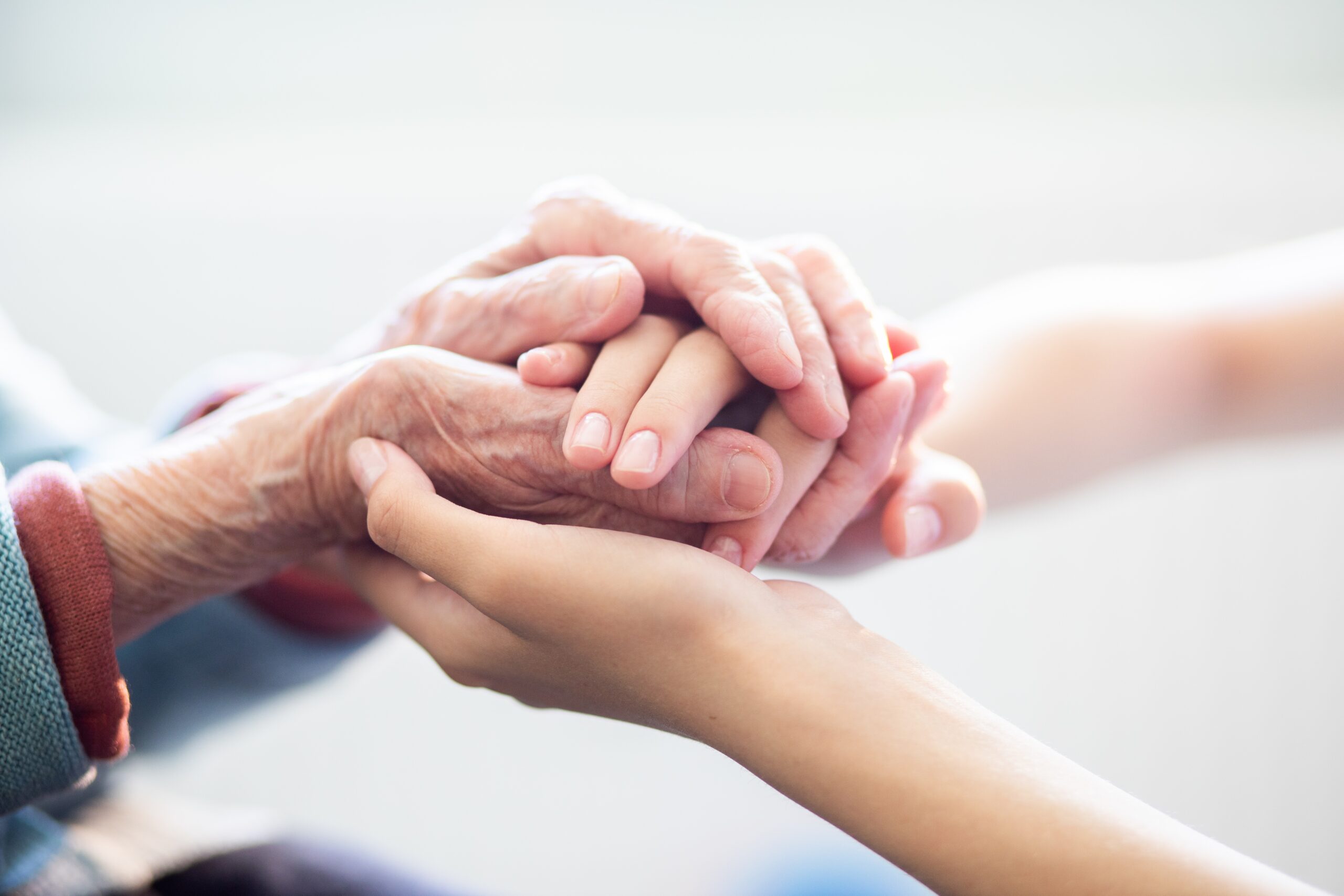 Caregiver holding an older adult’s hands in a memory care setting